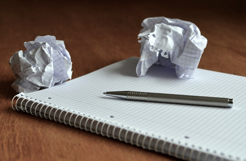 A note pad, pen and some screwed up paper